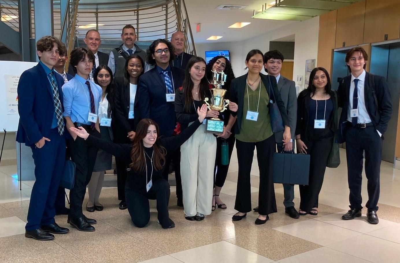 several student pose with a trophy