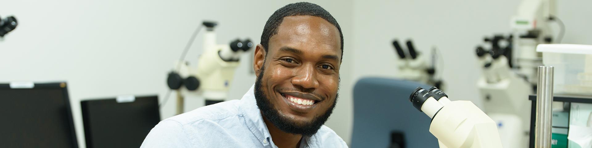 Post doc looking up from microscope and smiling